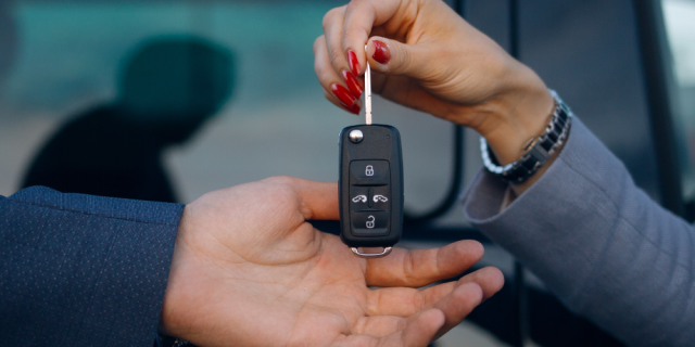 Hombre dando las llaves de un auto a otro. Cerró un contrato de renting