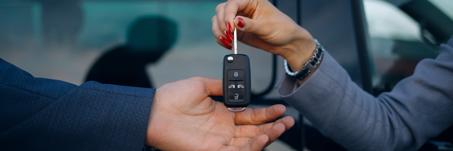 Hombre dando las llaves de un auto a otro. Cerró un contrato de renting